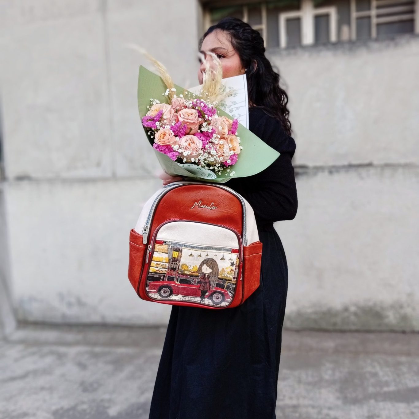 Nuevo Catálogo de Bolsas y Maletines Mujer con cabello rizado sosteniendo un ramo de flores y una mochila de diseño colorida.